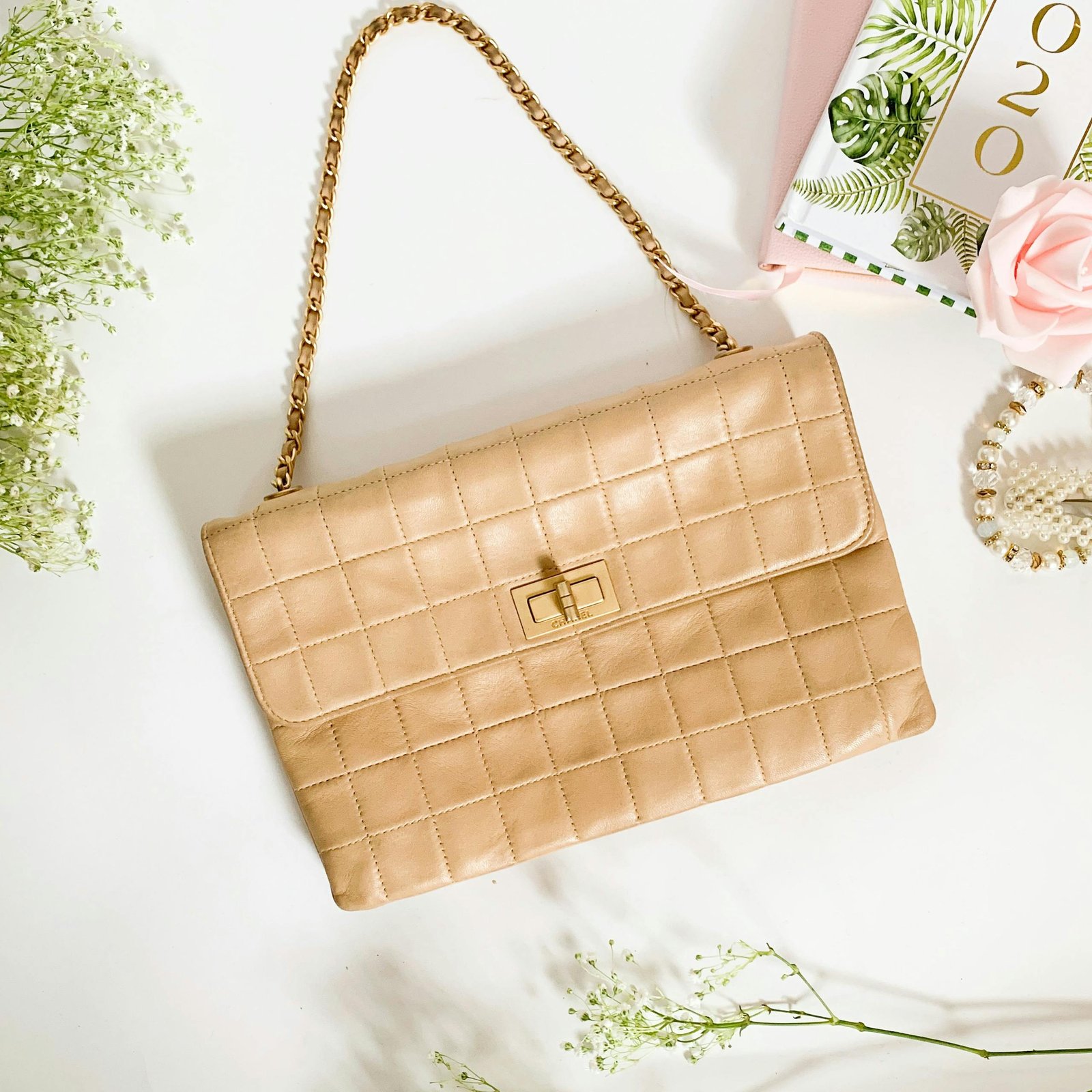 Stylish beige quilted purse with a chain strap, perfect for fashion enthusiasts.